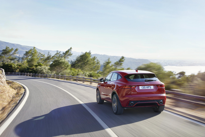 Red Jaguar E-PACE driving on a winding road with a scenic background of trees and mountains, showing the rear view including the license plate number 130 HPS and the Jaguar and E-PACE badges, suitable for used cars and new cars advertising.