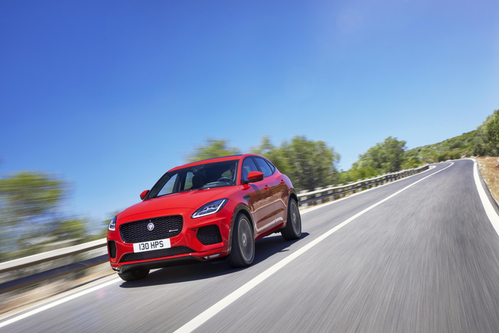 Red Jaguar E-PACE SUV driving on a winding country road under a clear blue sky, front view with licence plate reading '130 HPS', suitable for used cars and new cars listings.