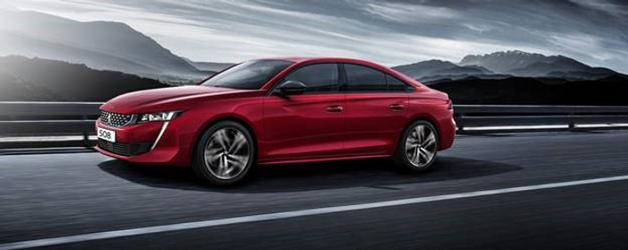 Red Peugeot 508 sedan driving on a highway with mountainous landscape in the background under a cloudy sky, showcasing a sleek and modern design, suitable for used cars or new cars options.