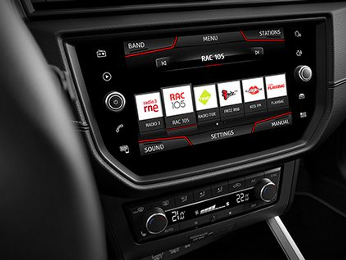 Car dashboard displaying the infotainment system tuned to radio station RAC 105, with options for radio stations including Radio 3, RAC 105, Radio Taxi, and others. Below the screen are climate control dials showing temperatures set to 21.0 and 22.0 degrees Celsius. The interior features a modern design typical of used cars and new cars.