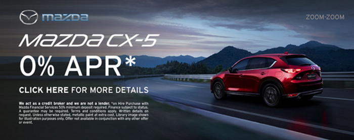Advertisement for Mazda CX-5 showing a red Mazda CX-5 SUV driving on a winding road at dusk with mountains in the background. The text highlights a 0% APR offer with a call to action to click for more details. Includes Mazda logo and slogan 'Zoom-Zoom'. Disclaimer mentions Mazda Finance Services, minimum deposit, finance subject to status, and offer limitations. Keywords relevant to used cars and new cars.