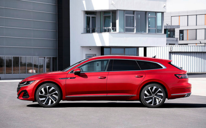 Red modern estate car parked in front of a commercial building with white and grey facade, showcasing sleek design and alloy wheels, suitable for used cars and new cars buyers.