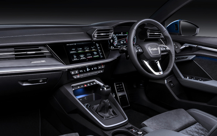 Interior view of a modern Audi car featuring a digital dashboard with speedometer and multimedia display showing menu options, a sporty leather steering wheel with Audi logo, manual gear stick, climate control panel, and stylish black and grey upholstery. This high-tech, clean car interior highlights features found in both used cars and new cars.