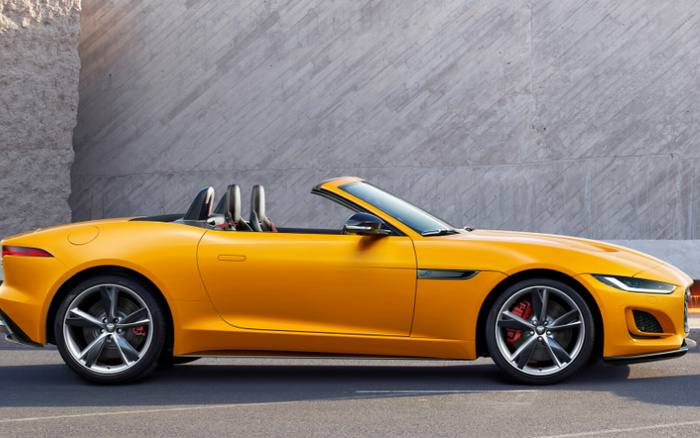 Bright yellow convertible sports car parked on a street with grey textured concrete wall background, suitable for advertising used cars and new cars.