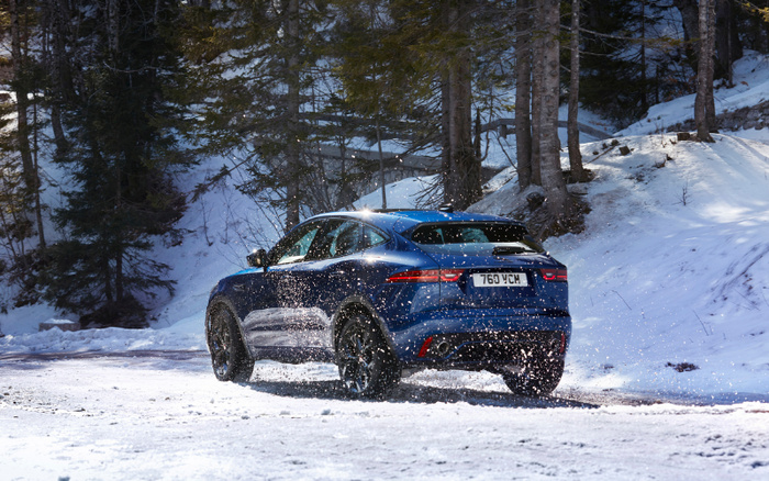 Blue sporty SUV driving on a snowy forest road with snow splashing around its wheels, surrounded by snow-covered trees in a winter landscape, showcasing a vehicle that could be featured in advertisements for used cars or new cars, with a visible license plate number 769 YCM.