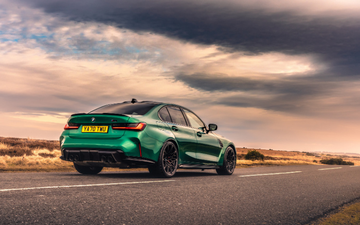 Green BMW M3 sports car with registration plate YA70 TWU parked on a country road under a dramatic cloudy sky with open fields in the background, illustrating a high-performance vehicle available among used cars and new cars.