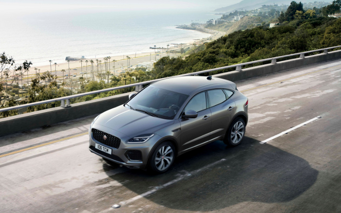 Silver Jaguar E-PACE driving on a coastal highway with a scenic ocean and beach view in the background, representing high-quality new cars and used cars options for car buyers.