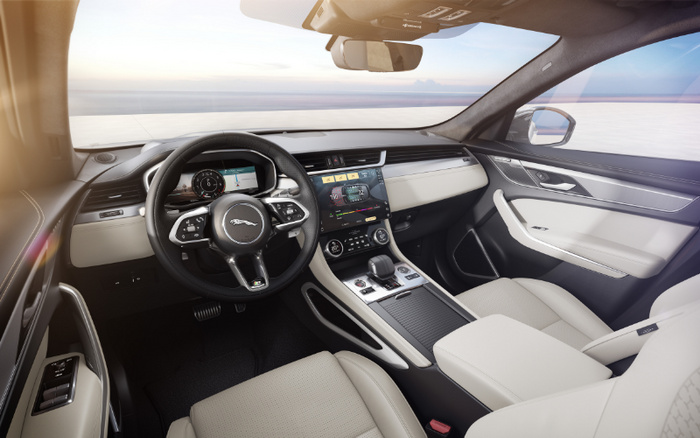 Interior view of a luxury Jaguar car showcasing a modern digital dashboard, touchscreen infotainment system, and beige leather seats inside a new car. The steering wheel features the Jaguar logo and various control buttons. Display screens show navigation and media controls. This elegant setting is ideal for those interested in new cars and used cars with advanced technology and premium design.