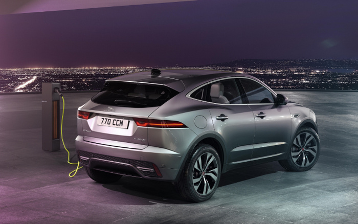 Silver Jaguar I-PACE electric car with registration plate 770 CCM charging at a modern charging station on a rooftop at night overlooking city lights, showcasing a sleek design and electric vehicle technology, ideal for buyers interested in used cars and new cars.