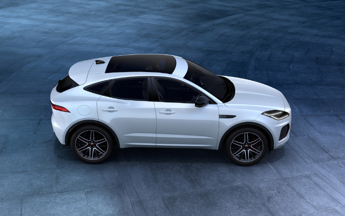 Side view of a white luxury SUV parked on a textured blue stone surface, showcasing sleek design, dark tinted windows, black alloy wheels, and aerodynamic features, ideal for advertising used cars and new cars.