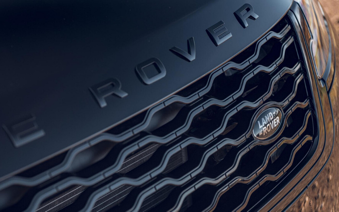 Close-up image of the front grille and hood of a Land Rover vehicle, showing the 'LAND ROVER' badge on the grille and the partially visible 'ROVER' lettering on the hood, highlighting the car's sleek design, suitable for used cars and new cars listings.