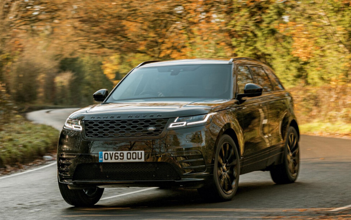 Black Range Rover Velar driving on a winding road with autumn foliage in the background, showing front grille, LED headlights, and UK license plate OV69 OOU, suitable for used cars and new cars listings.