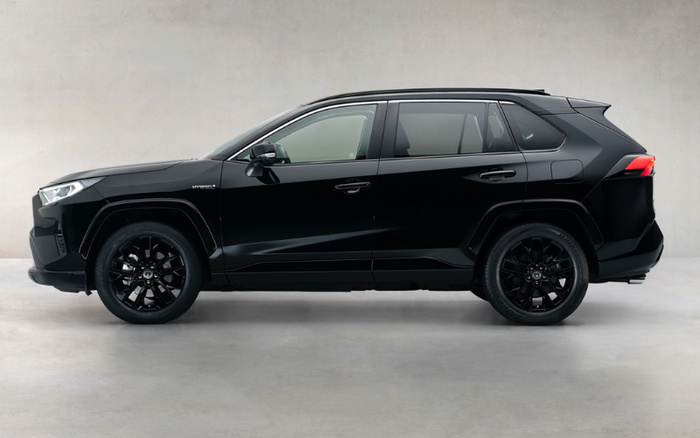 Side view of a sleek black hybrid SUV with tinted windows and black alloy wheels, parked indoors against a plain light grey wall, showcasing a modern design ideal for buyers searching for used cars and new cars.