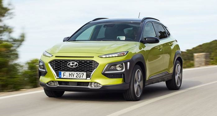 Green Hyundai Kona driving on a road with a German license plate reading F HY 207, showcasing a modern compact SUV design, ideal for both new cars and used cars buyers looking for stylish and efficient vehicles.