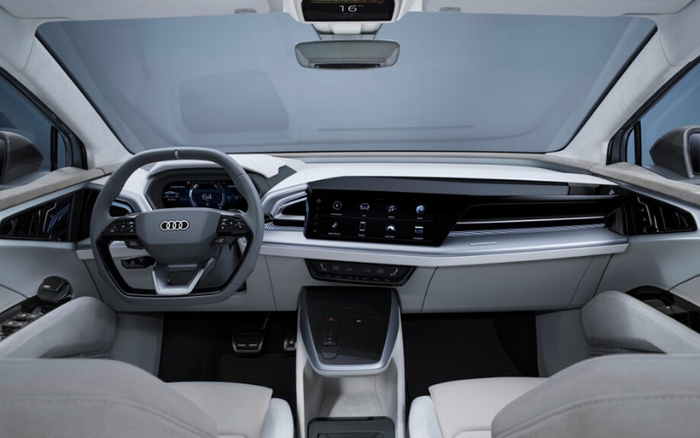 Interior view of a modern Audi car showcasing the digital dashboard, multifunction steering wheel with Audi logo, and a wide central touchscreen display. The dashboard displays a speed of 64 km/h and various control icons. The cabin features light grey seats and door panels, highlighting a futuristic and minimalistic design. This image is relevant for used cars or new cars with advanced technology and luxury interior features.