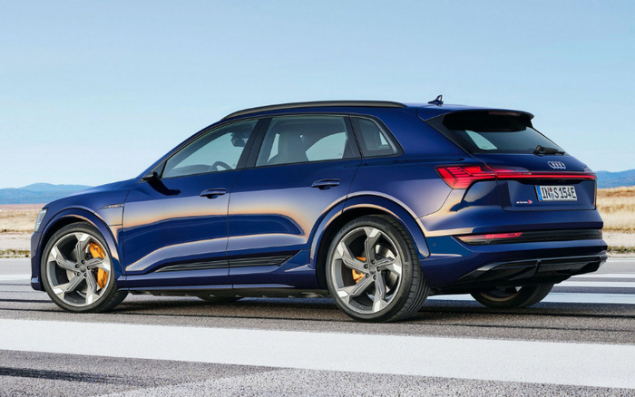 Blue Audi e-tron S electric SUV parked on a road with mountainous background, showcasing sleek modern design, distinctive alloy wheels with orange brake calipers, and rear badge with the model name 'e-tron S'. Perfect example of new cars available alongside used cars in the market.