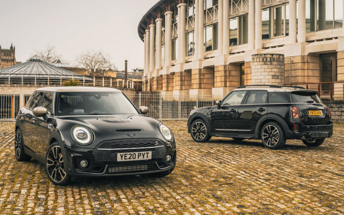 Two black Mini Cooper cars parked on a cobblestone surface in front of a classical building with columns. The car on the left is a front view with the registration plate YE20 PYT, and the car on the right shows the rear and side with the plate YX70 RYN. The scene is set in an outdoor urban environment, ideal for advertising used cars and new cars.
