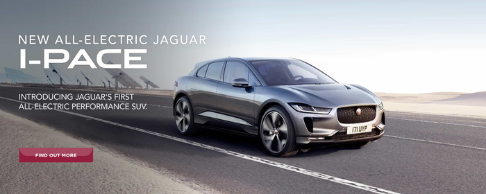New all-electric Jaguar I-PACE driving on a deserted road with desert landscape and solar panels in the background. Text reads: 'New all-electric Jaguar I-PACE. Introducing Jaguar's first all-electric performance SUV.' A red button below the text says 'Find out more'. The image promotes new cars, specifically the electric Jaguar I-PACE.