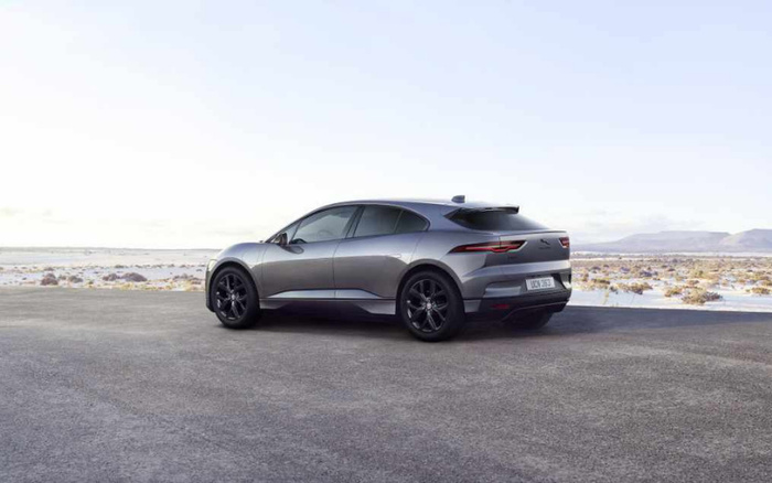 Sleek grey electric SUV parked on an open paved area with a desert landscape and mountains in the background, highlighting modern new cars and used cars for sale.
