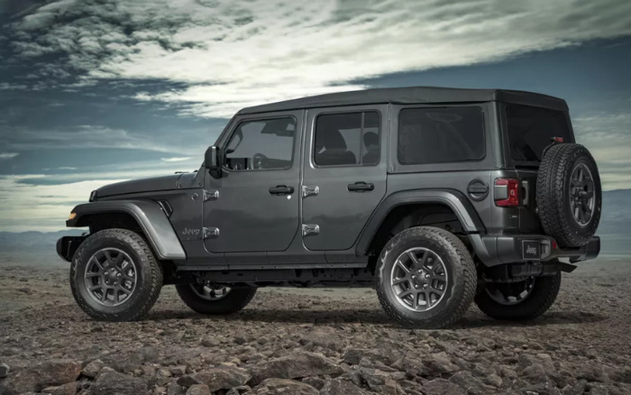 Grey Jeep Wrangler 4-door vehicle parked on rocky terrain under a cloudy sky, showcasing rugged design and off-road capability, ideal representation for used cars and new cars.