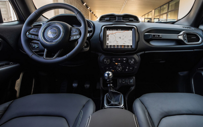 Interior view of a Jeep car featuring a steering wheel with Jeep logo, touchscreen GPS navigation displaying a map, climate control buttons, gear stick, and black leather seats with white stitching. The dashboard includes modern control buttons and vents, showcasing a clean and stylish design ideal for buyers interested in used cars or new cars.