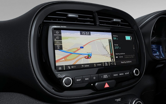 Car dashboard featuring a Harman Kardon infotainment system displaying a navigation map with directions, the time 15:57, battery at 84%, range of 237 miles, and nearby station information. The system has buttons labeled MAP, NAV, SEEK TRACK, RADIO, MEDIA, and SETUP. The dashboard is part of a modern vehicle interior highlighting advanced technology, suitable for used cars and new cars.