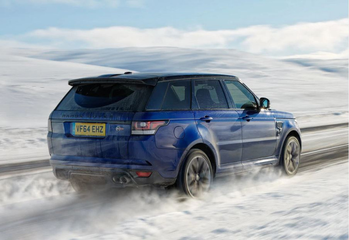 Blue Range Rover SUV driving on a snowy road with snow kicking up around the wheels, vehicle registration plate VF64 EHZ visible, showcasing a robust new car ideal for winter conditions, suitable for advertising used cars and new cars in challenging weather environments.
