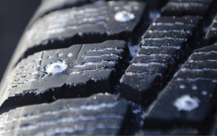 Close-up view of a car tyre tread with small ice and snow particles lodged in the grooves, highlighting the detail and grip of the tyre surface, relevant for both used cars and new cars maintenance and safety.