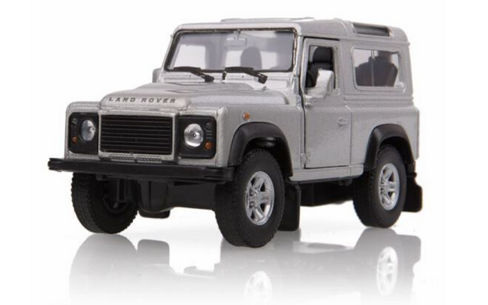 Silver Land Rover Defender model car photographed on a reflective white surface, showcasing detailed front view with Land Rover logo on the bonnet and rugged tyre tread. Ideal representation for used cars and new cars sales.