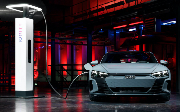 Front view of a grey Audi electric car charging at an Ionity charging station inside a dimly lit industrial building with red and blue lighting. The image showcases a modern electric vehicle and charging infrastructure, relevant for new cars and used cars in the electric vehicle market.