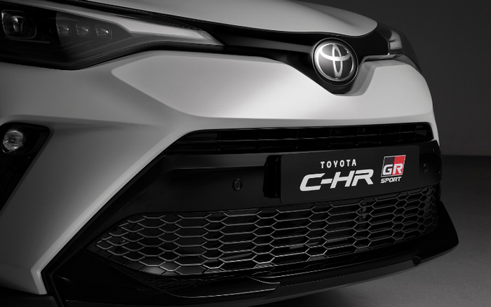 Close-up of the front of a white Toyota C-HR GR Sport car, highlighting the Toyota emblem and the model badge on the grille, suitable for advertising used cars and new cars.