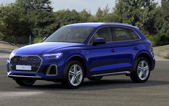 Blue Audi Q5 parked on a paved area with trees and greenery in the background, showcasing a sleek design and modern LED headlights, perfect example of used cars or new cars available for sale.