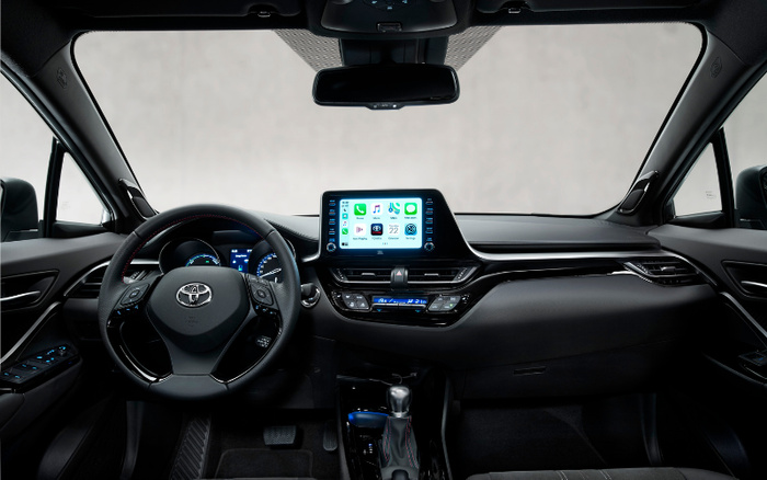 Interior view of a Toyota car dashboard featuring a steering wheel with Toyota logo, a digital instrument cluster, and a central touchscreen display showing apps including Phone, Music, Maps, and Messages. The climate control panel below the screen displays temperatures set to 21°C. This modern and sleek interior design is ideal for both used cars and new cars buyers seeking advanced technology and comfort.
