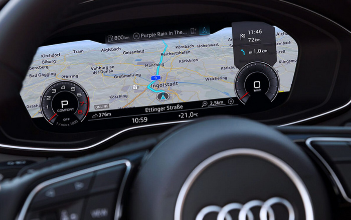 Digital dashboard display of an Audi car showing navigation map centered on Ingolstadt, with current time 10:59, outside temperature 21.0°C, and driving mode set to Comfort. The map shows surrounding locations including Geisenfeld, Karlskron, and Vohburg an der Donau. Speedometer reads 0 km/h and information indicates next turn in 1.0 km. Suitable for illustrating features of used cars or new cars with advanced navigation and digital instrument panel.