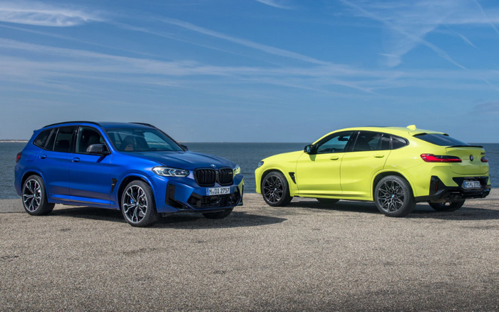 Two BMW SUVs parked side by side on a gravel surface by the sea under a clear blue sky. The vehicle on the left is a blue BMW X3, showcasing its front and side profile with distinct kidney grilles and sporty alloy wheels. The vehicle on the right is a yellow BMW X4, shown from the rear and side, featuring sleek taillights and a sloping roofline. Both vehicles represent premium used cars and new cars models, highlighting sporty design and modern features, ideal for customers looking for quality used cars or new cars.