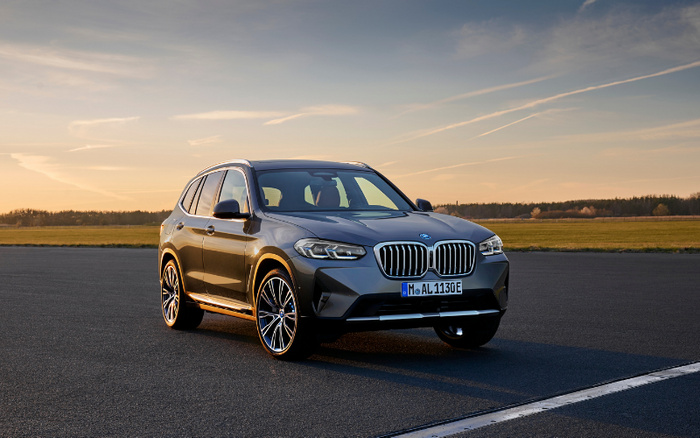 Grey BMW SUV parked on an empty runway during sunset with clear sky and fields in the background, showcasing a modern new car model with European license plate, ideal for used cars or new cars buyers.