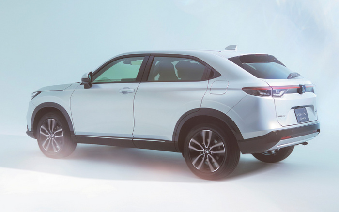 Side and rear view of a white Honda HR-V e:HEV new car in a studio setting, showcasing sleek design and alloy wheels, suitable for buyers interested in used cars and new cars.