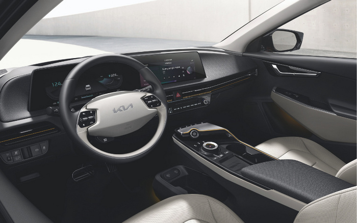 Interior view of a new Kia car showcasing a modern steering wheel with Kia logo, digital instrument cluster displaying 124 km/h speed, and a central touchscreen infotainment system. The sleek dashboard and centre console feature touch controls and rotary dials, highlighting the advanced technology and design of new cars. This image represents the high-quality interior typical of both used cars and new cars.