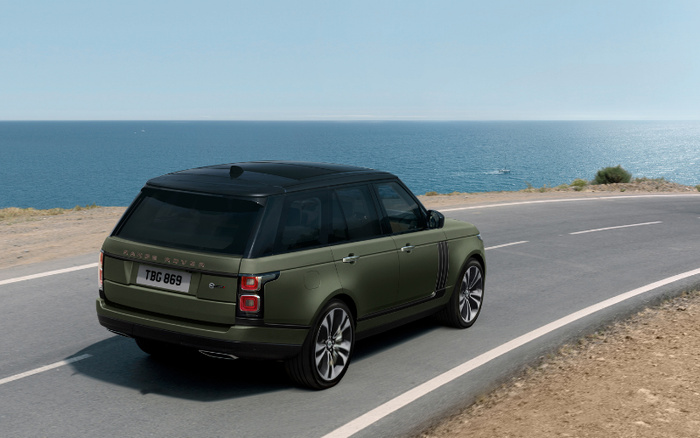 Green Range Rover with licence plate TBG 869 driving on a coastal road with the ocean in the background, representing new cars and used cars in a scenic setting.