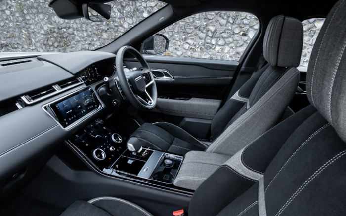 Interior view of a modern car showcasing the driver's seat, front passenger seat, dashboard, and centre console. Features include a digital touchscreen display, leather and fabric seats with contrast stitching, a gear selector, and climate control dials. The car is right-hand drive, emphasising luxury and comfort. This image is relevant for used cars and new cars, highlighting contemporary vehicle design and advanced technology.