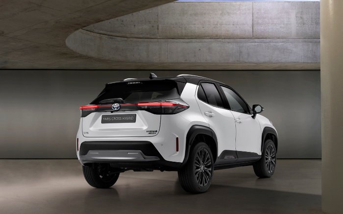 White Toyota Yaris Cross Hybrid parked in a modern concrete indoor space, rear three-quarter view showing hybrid and AWD badges, highlighting a new car model ideal for buyers interested in used cars or new cars.