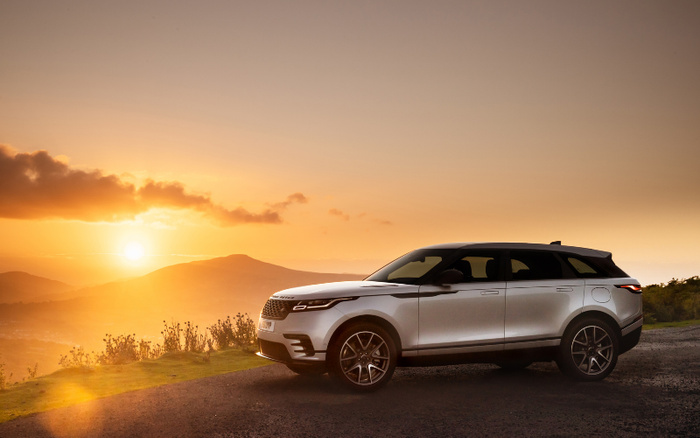 Silver SUV parked on a roadside with a scenic sunset view over rolling hills and a clear sky, representing used cars and new cars in a natural, picturesque setting.