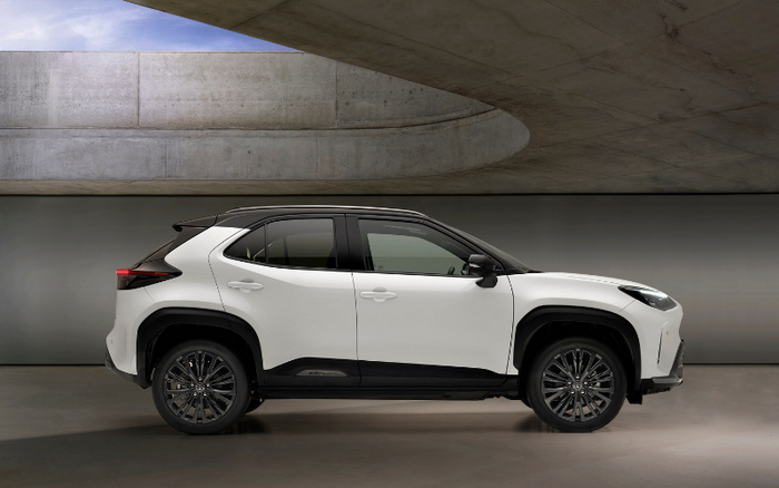 Side view of a white and black modern compact SUV car parked indoors under a curved concrete ceiling, showcasing sleek design and dark alloy wheels, suitable for advertising used cars and new cars.