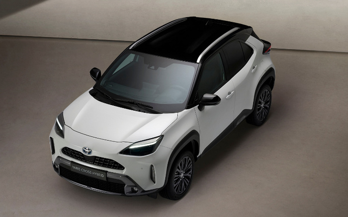 White Toyota Yaris Cross Hybrid new car with black roof and tinted windows shown from a high front angle in a neutral studio setting, highlighting sleek headlights and modern design, suitable for both used cars and new cars market.