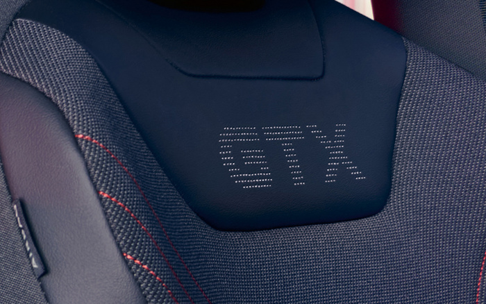 Close-up of a car seat with black fabric and leather sections, featuring red stitching and perforated leather with the embossed letters 'GTX'. Ideal for used cars and new cars interiors showcasing sporty seat design.