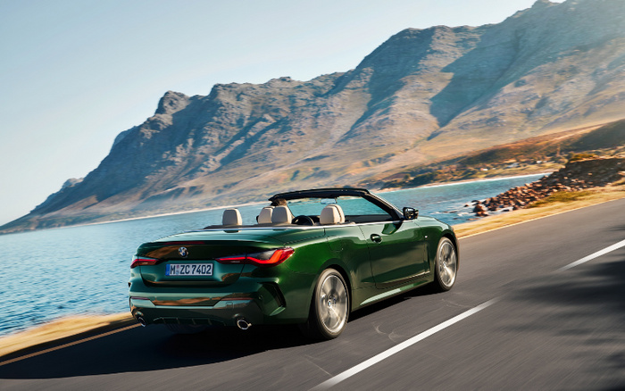 Green BMW convertible driving on a coastal road with mountains and water in the background, showcasing a new car model with license plate M-ZC 7402, ideal for buyers interested in used cars and new cars.
