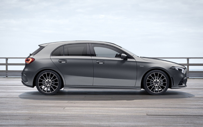 Side view of a modern grey hatchback car parked on a wooden deck with railings and a cloudy sky in the background, suitable for showcasing new cars and used cars in automotive sales.