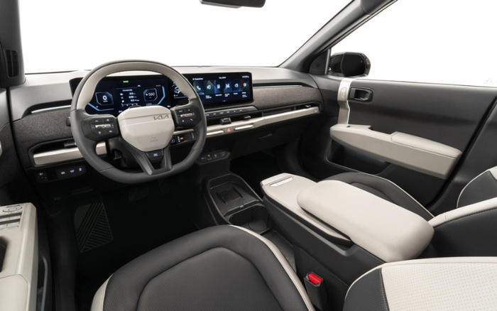 Interior view of a modern car featuring a digital instrument cluster and touchscreen infotainment system, a grey and beige steering wheel with the Kia logo, black and beige seats, and a sleek dashboard design. This spacious cabin highlights advanced technology and a comfortable layout, suitable for both used cars and new cars buyers.