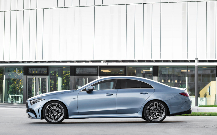 Blue luxury sedan parked in front of a modern glass building, showcasing a sleek design suitable for used cars or new cars purchase options.