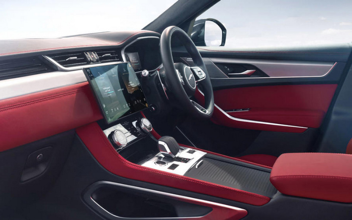 Interior view of a modern car with red and black leather seats, a digital touchscreen display showing navigation and media options, and a sporty steering wheel featuring the Jaguar logo. The dashboard and centre console have a sleek design with chrome accents, highlighting a high-end, sophisticated vehicle interior suitable for both used cars and new cars buyers.